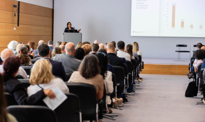 Vista geral da plateia na apresentação do Relatório com a Dra. Sara Medina, Sub-inspetora Geral da IGAC, a falar para o público